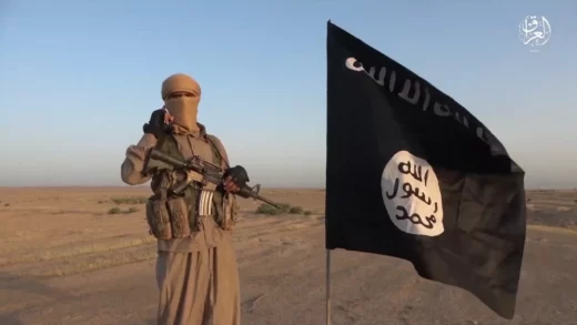 Beväpnad IS-krigare står intill IS-flagga