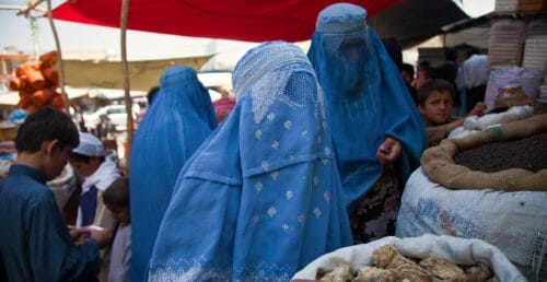 Kvinnor i burka köper varor på marknaden