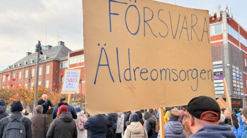 En person håller ett plakat med texten "Försvara äldreomsorgen"