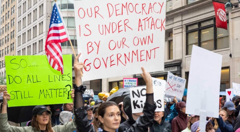 En demonstrant håller i en skylt med texten "Vår demokrati angrips av vår egen regering" (på engelska)