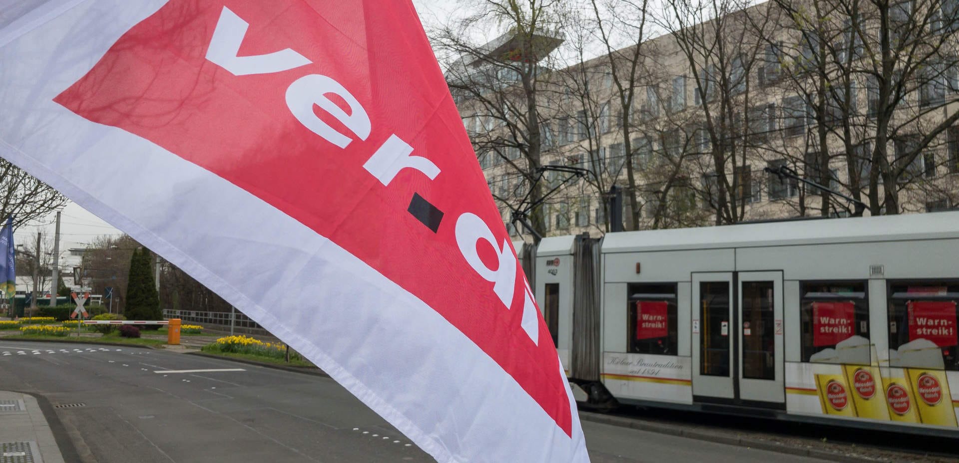En flagga från fackförbundet Verdi vajar framför en spårvagn med texten "varningsstrejk" klistrad på rutorna