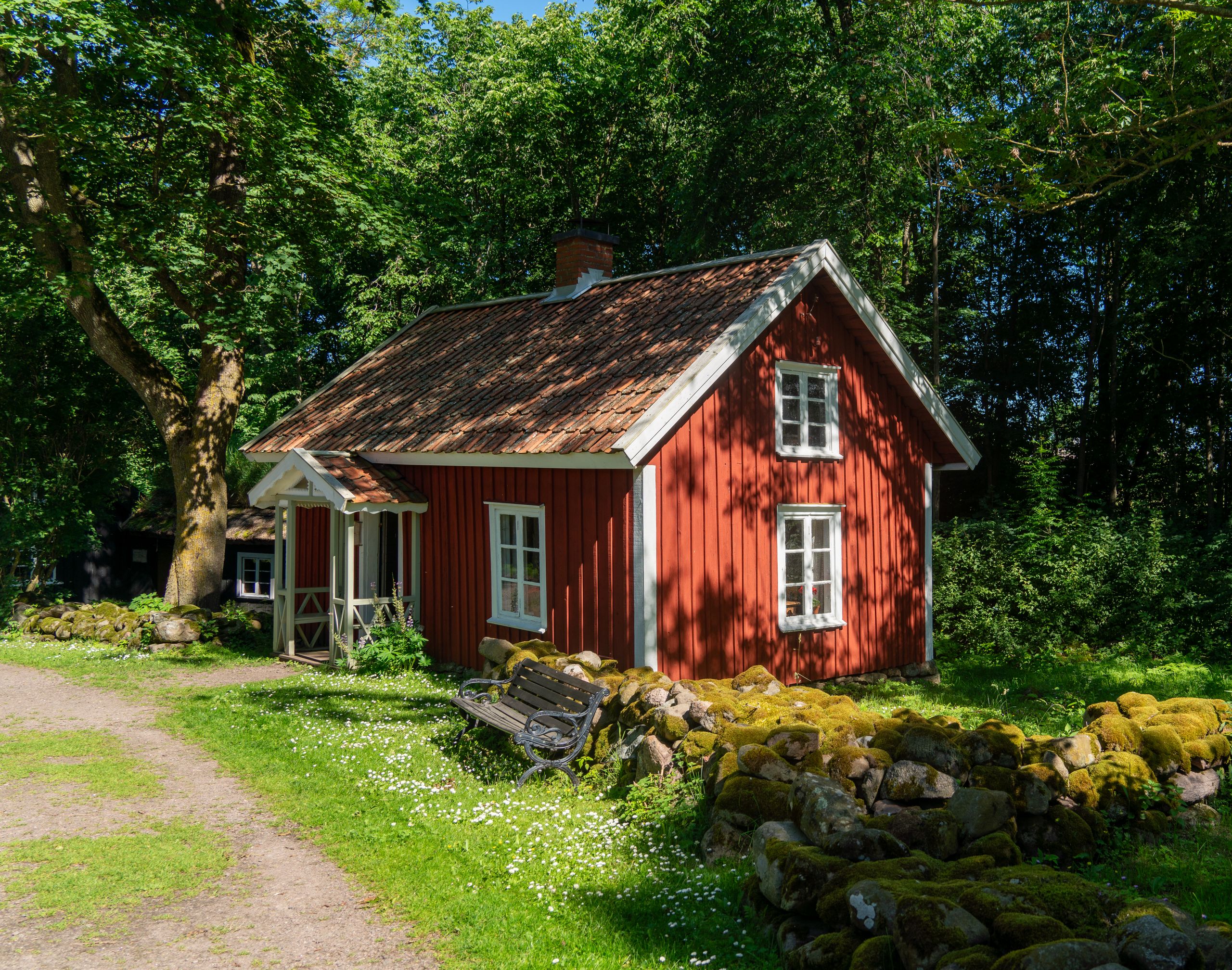 Quaint red cottage surrounded by lush greenery in Falköping, Sweden.